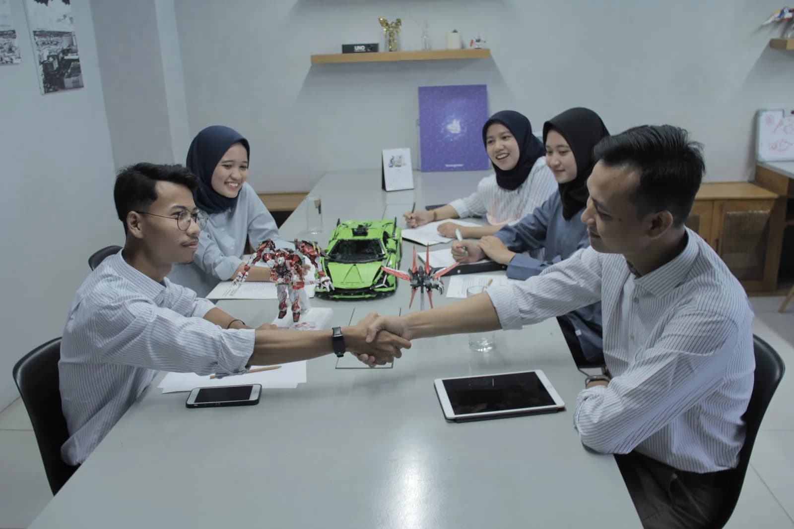 Dua orang berjabat tangan di ruang diskusi