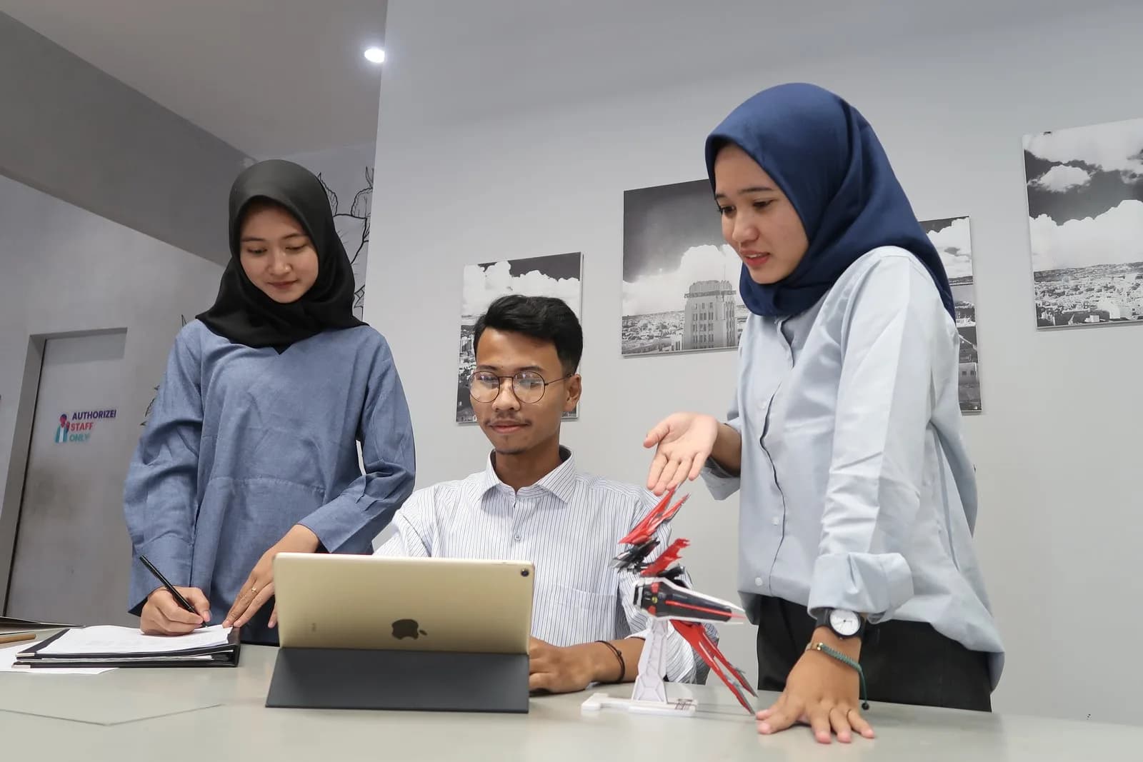 Tiga mahasiswa bekerja dengan laptop